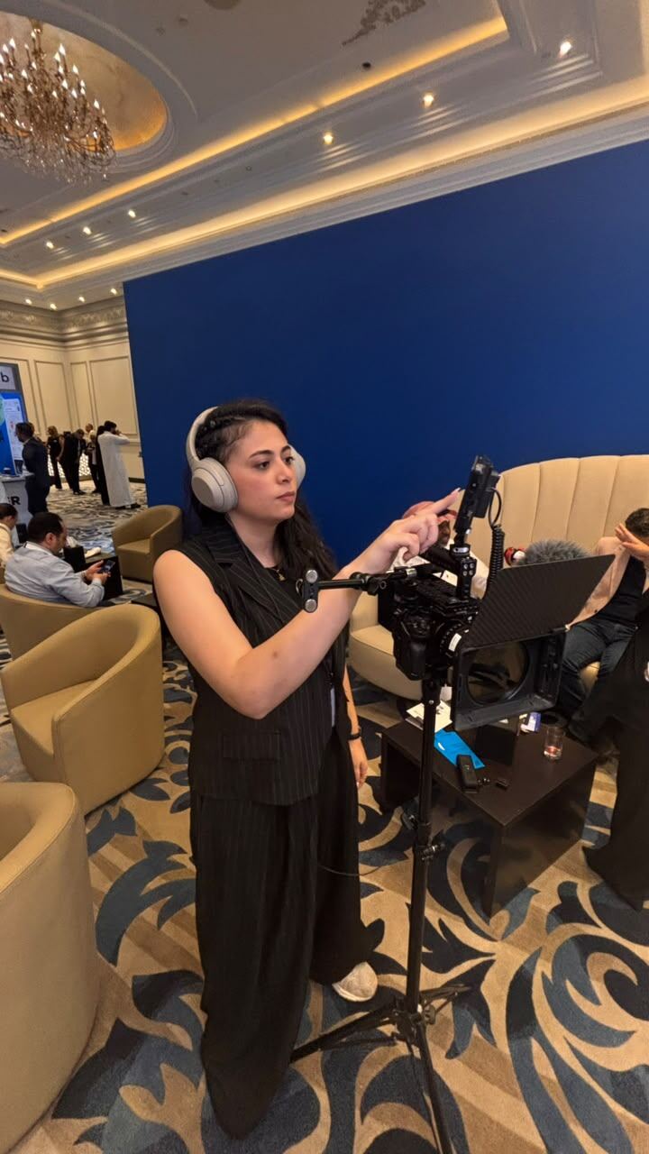 Behind the scenes — Reem filming recap footage on the event floor with a camera rig and headphones.